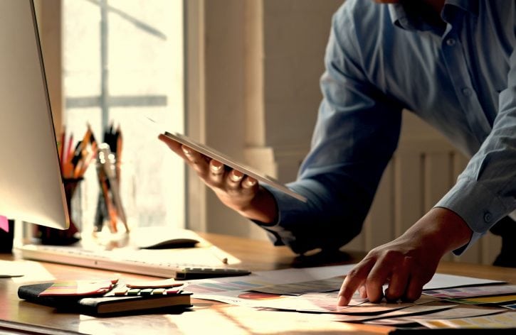 finger-tips-on-a-paper-on-a-desk-hand-holds-a-tablet